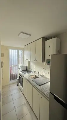 a kitchen with white cabinets and a sink and a refrigerator at Av Poeta Lugones - Nueva Córdoba in Cordoba