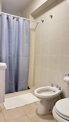 a bathroom with a toilet and a blue shower curtain at Av Poeta Lugones - Nueva Córdoba in Cordoba