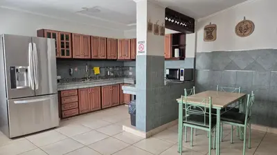 a kitchen with a table and a stainless steel refrigerator at Casa colores fotheringham in Río Cuarto