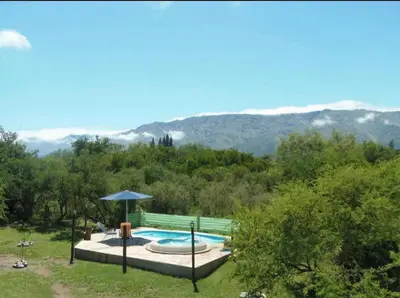 a swimming pool with an umbrella and mountains in the background at Cabañas Chakra Raiz in Pantanillo