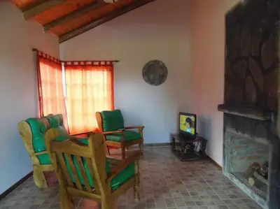 a living room with green chairs and a fireplace at Cabañas Chakra Raiz in Pantanillo