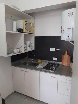 a kitchen with white cabinets and a sink and a microwave at Dean Funes - Distrito monoambiente in Cordoba