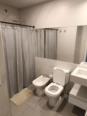 a white bathroom with a toilet and a sink at Departamento moderno en Barrio General Paz in Cordoba