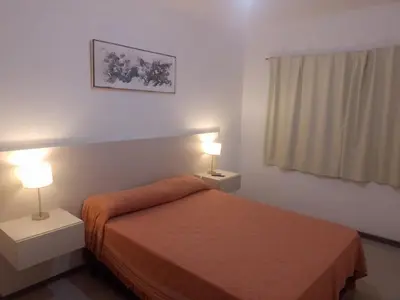 a bedroom with a bed and two night stands with lamps at Atardecer urbano en el corazón de Carlos Paz in Villa Carlos Paz