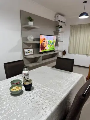 a dining room with a white table with a television at Atardecer urbano en el corazón de Carlos Paz in Villa Carlos Paz