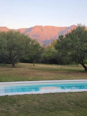 a swimming pool with trees and mountains in the background at Descanso Serrano in Las Rabonas