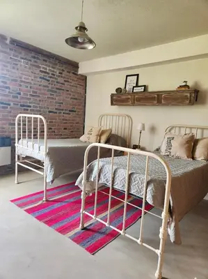 a bedroom with two beds and a brick wall at Descanso Serrano in Las Rabonas