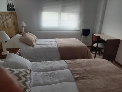 a bedroom with two beds and a desk and a window at Costanera in Río Cuarto
