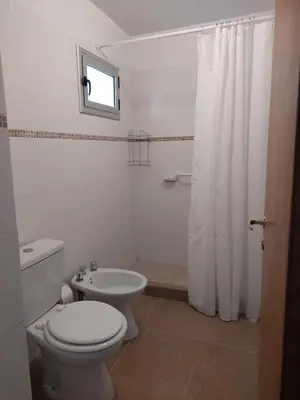a white bathroom with a toilet and a sink at Costanera in Río Cuarto