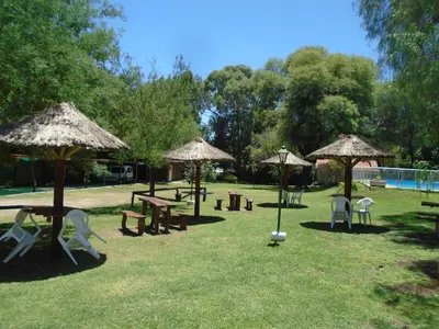 a park with tables and chairs and umbrellas at Hostería de los Césares in Merlo
