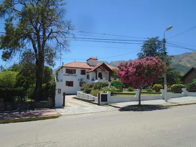 a white house with a fence and a pink tree at Hostería de los Césares in Merlo