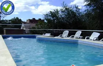 a swimming pool with white chairs and a swimming pool at Terrazas del Diquecito in Villa Carlos Paz