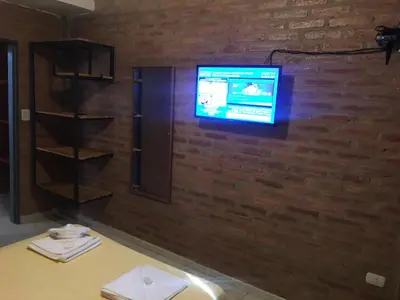 a tv on a brick wall with a table and a tv on it at Terrazas del Diquecito in Villa Carlos Paz
