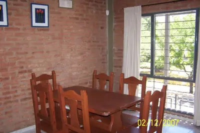 a dining room table and chairs with a brick wall at Terrazas del Diquecito in Villa Carlos Paz
