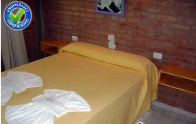 a yellow bed in a bedroom with a brick wall at Terrazas del Diquecito in Villa Carlos Paz