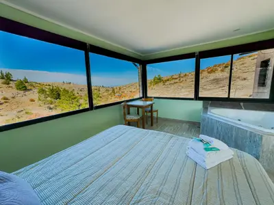 a bedroom with a bed and a tub and windows at Cuesta de las Piedras in La Cumbrecita
