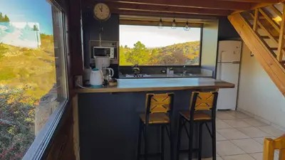 a kitchen with two stools at a counter with a window at Cuesta de las Piedras in La Cumbrecita
