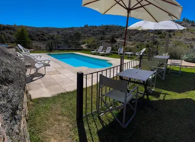a table with an umbrella next to a swimming pool at Cuesta de las Piedras in La Cumbrecita
