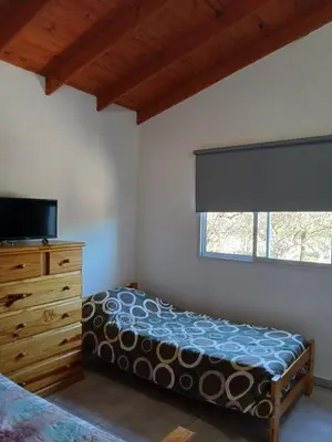a bedroom with a bed and a dresser and a window at La Porteña in Cortaderas
