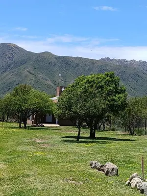 a field with trees and a house with mountains in the background at La Porteña in Cortaderas