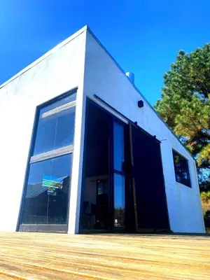 a white building with large windows on a clear day at Kururu Cabaña en Villa Yacanto con vista a las sierras in Villa Yacanto