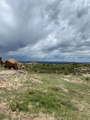 a field with grass and rocks and a cloudy sky at Casa Cian in Mina Clavero