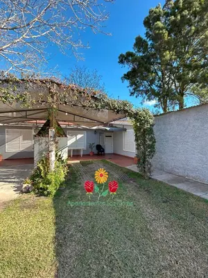 a house with a garden with two flowers in the yard at Apartamentos Las Flores in Villa Carlos Paz