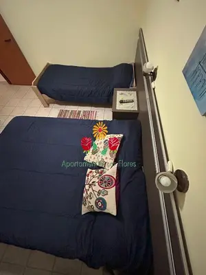 a bedroom with two beds with blue sheets and a lamp at Apartamentos Las Flores in Villa Carlos Paz