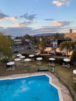 a swimming pool with umbrellas and tables and chairs at Departamento con hermosa vista en Carlos Paz in La Cuesta