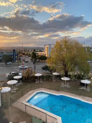 a swimming pool with umbrellas and a parking lot at Departamento con hermosa vista en Carlos Paz in La Cuesta