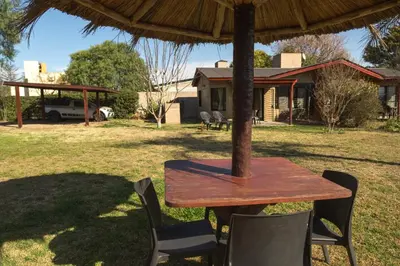 a wooden table and chairs under an umbrella at Complejo Lago Serrano in Villa Rumipal