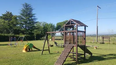 a playground with a slide and a swing set at Complejo Lago Serrano in Villa Rumipal