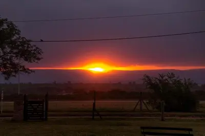 a sunset over a park with a bench in a field at Complejo Lago Serrano in Villa Rumipal
