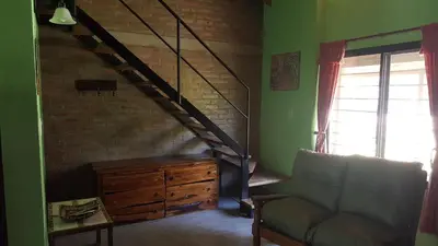 a living room with a staircase and a couch at Complejo Lago Serrano in Villa Rumipal