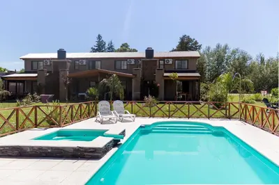 a swimming pool with two chairs and a house at Complejo Lago Serrano in Villa Rumipal