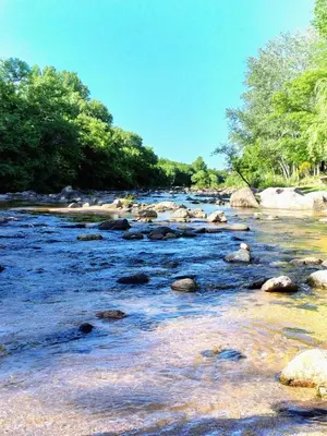 a river with rocks and trees in the background at Cabañas Las Luceros in San Antonio de Arredondo