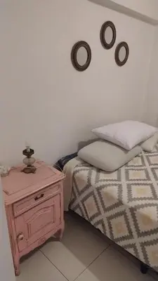 a bedroom with a bed and a nightstand with a clock on the wall at Departamento amplio, Zona Nueva Cba , A cien metros de la terminal Buss in Cordoba