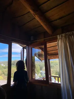 a person sitting in a room looking out the window at Cabañas Ensueño in Villa Carlos Paz