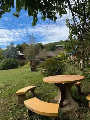 a wooden picnic table and benches in a yard at Cabañas Ensueño in Villa Carlos Paz