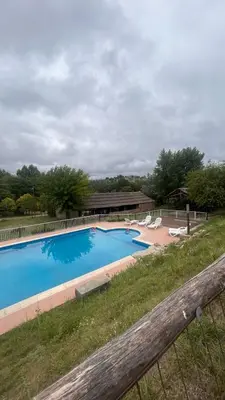 a large blue swimming pool with chairs and a house at Cabañas Ensueño in Villa Carlos Paz