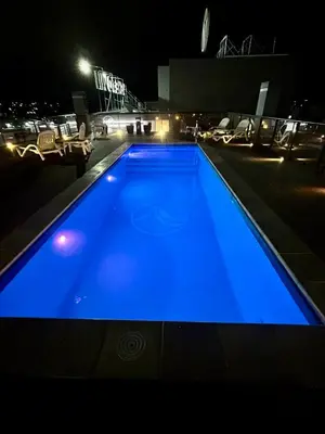 a large blue swimming pool at night at Flat with Pool, Gym & Great Views in Villa Carlos Paz
