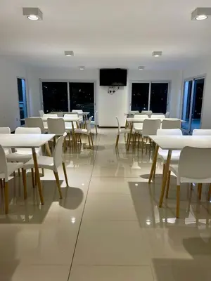 a dining room with white tables and white chairs at Flat with Pool, Gym & Great Views in Villa Carlos Paz