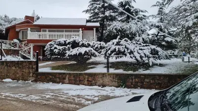 a house covered in snow with a car parked in front at La Casa del Lago in Villa Santa Cruz del Lago