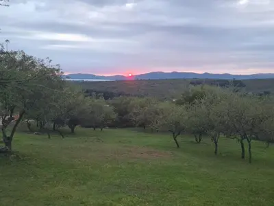 a field with trees and the sunset in the background at Las Negritas, Casas de Montaña in La Estancia