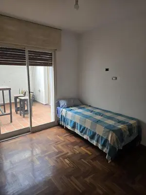 a bedroom with a bed and a table and a patio at Departamento - Cerro de las Rosas, Cordoba - 5 personas in Cordoba
