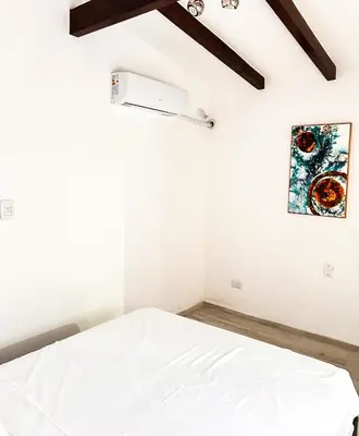 a bedroom with a white bed and a painting on the wall at Cabañas Antartida in Villa Carlos Paz