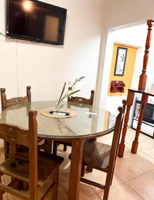 a dining room table and chairs with a television on the wall at Cabañas Antartida in Villa Carlos Paz