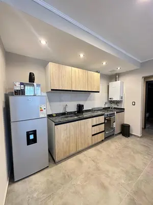 a kitchen with a white refrigerator and wooden cabinets at Departamentos Sol y Lago in Villa Carlos Paz