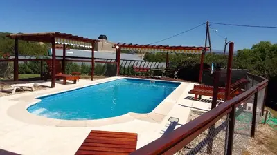 a swimming pool with a pergola next to a house at Cabañas Mi Capricho in Santa Rosa de Calamuchita