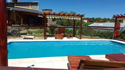 a swimming pool with a pergola and a house at Cabañas Mi Capricho in Santa Rosa de Calamuchita